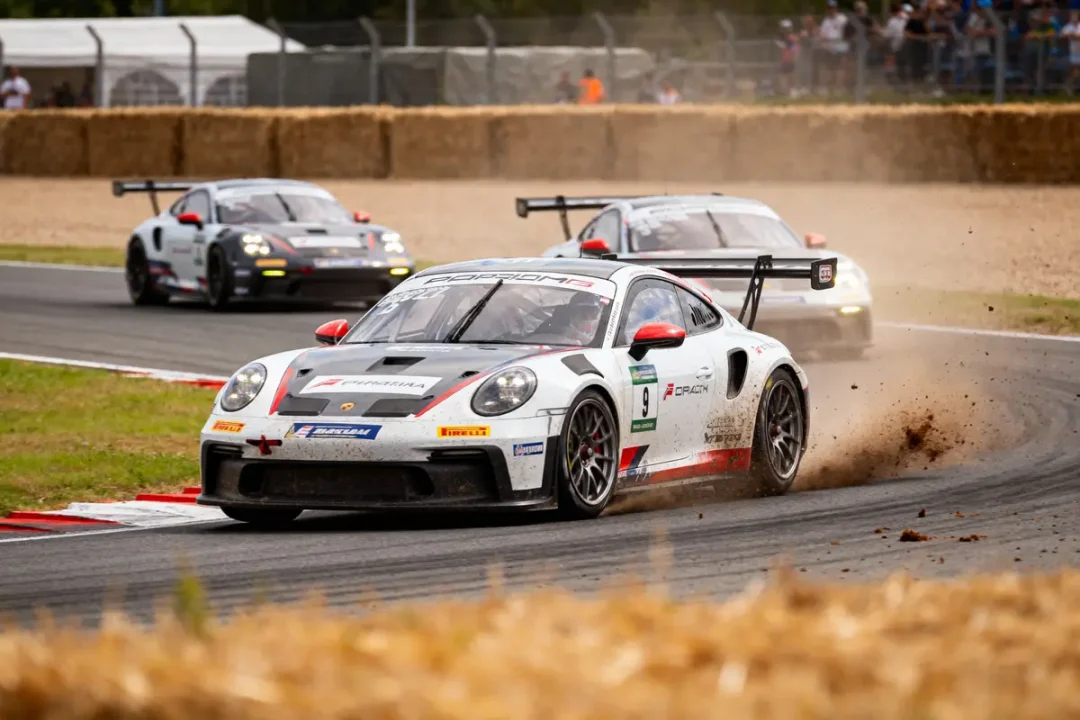 Trois voitures de course Porsche sur circuit, soulevant poussière et virant à pleine vitesse.