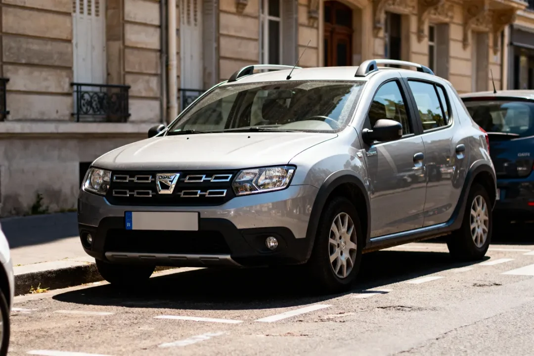 SUV argenté Dacia stationné dans une rue, devant un bâtiment ancien.