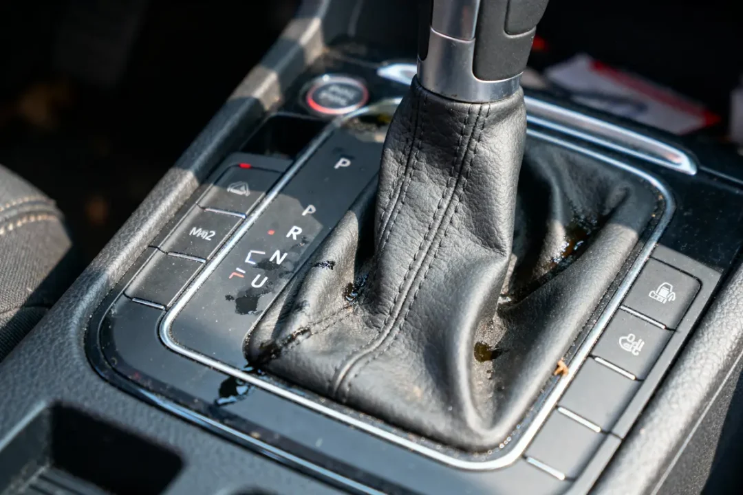 Levier de vitesses automatique en cuir taché, avec boutons de commande exposés en gros plan dans une voiture.