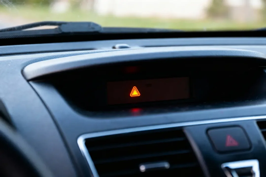 Tableau de bord de voiture avec voyant lumineux de danger orange allumé et bouton d'avertissement.