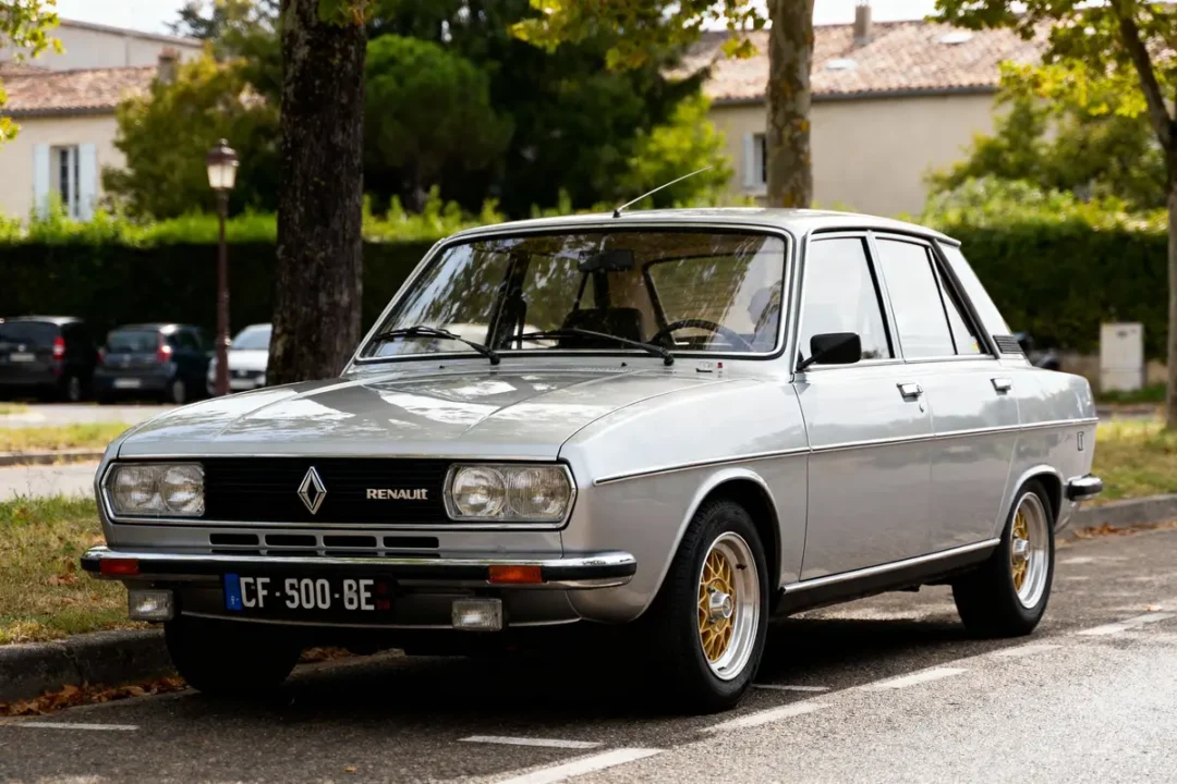 Voiture classique Renault grise stationnée sur route ombragée, avec plaques d'immatriculation françaises et verdure en arrière-plan.