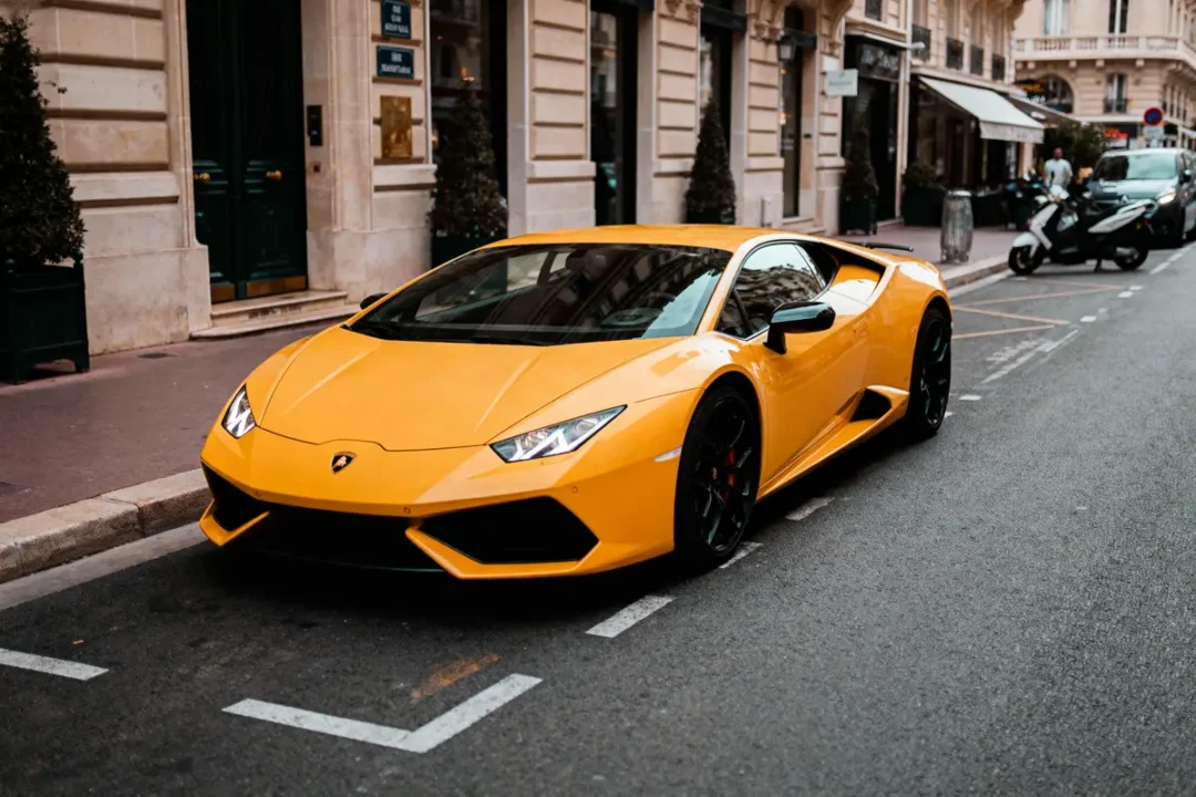 Voiture de sport jaune garée dans une rue bordée de bâtiments élégants.