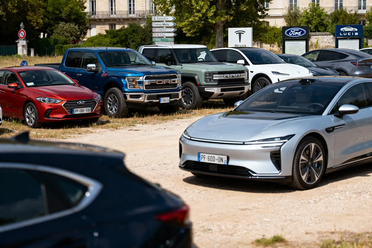 Plusieurs voitures de différentes marques garées en extérieur près de panneaux signalétiques automobiles.