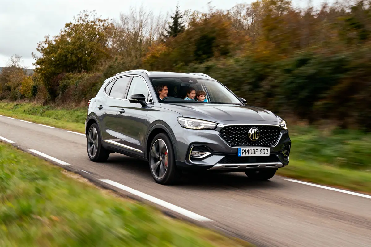 SUV gris roulant sur une route de campagne, avec trois personnes à l'intérieur.