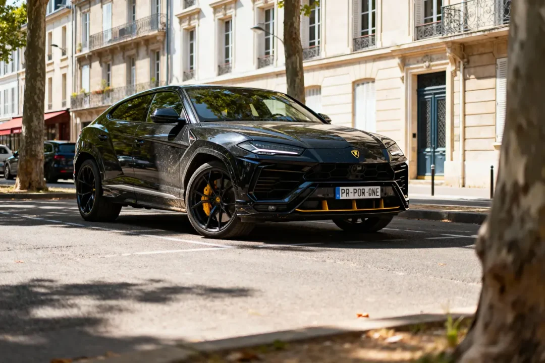 SUV noir garé dans une rue bordée d'immeubles classiques, arbres et lumière d'été douce. Plaque PR-POR-ONE.