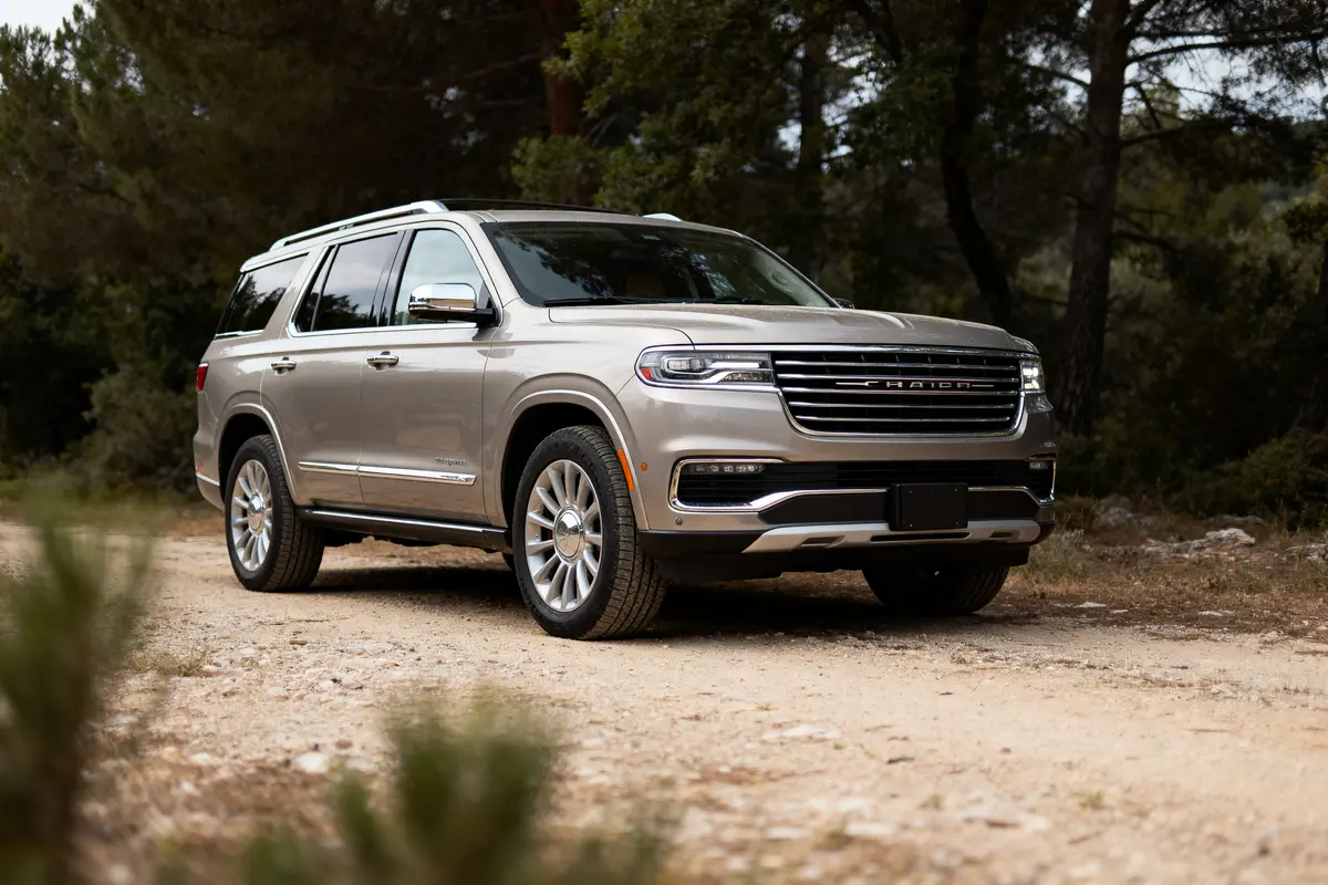 SUV argent garé sur un chemin de terre, entouré d'arbres, journée ensoleillée. Véhicule moderne et robuste.