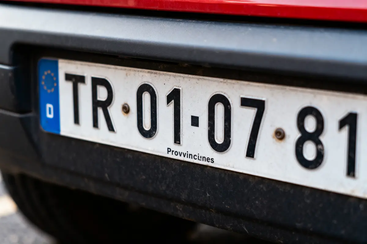Plaque d'immatriculation européenne allemande sur une voiture rouge stationnée.