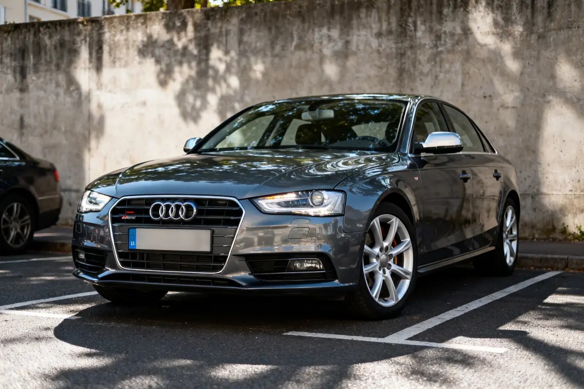 Voiture grise Audi A4 garée sur un parking ensoleillé