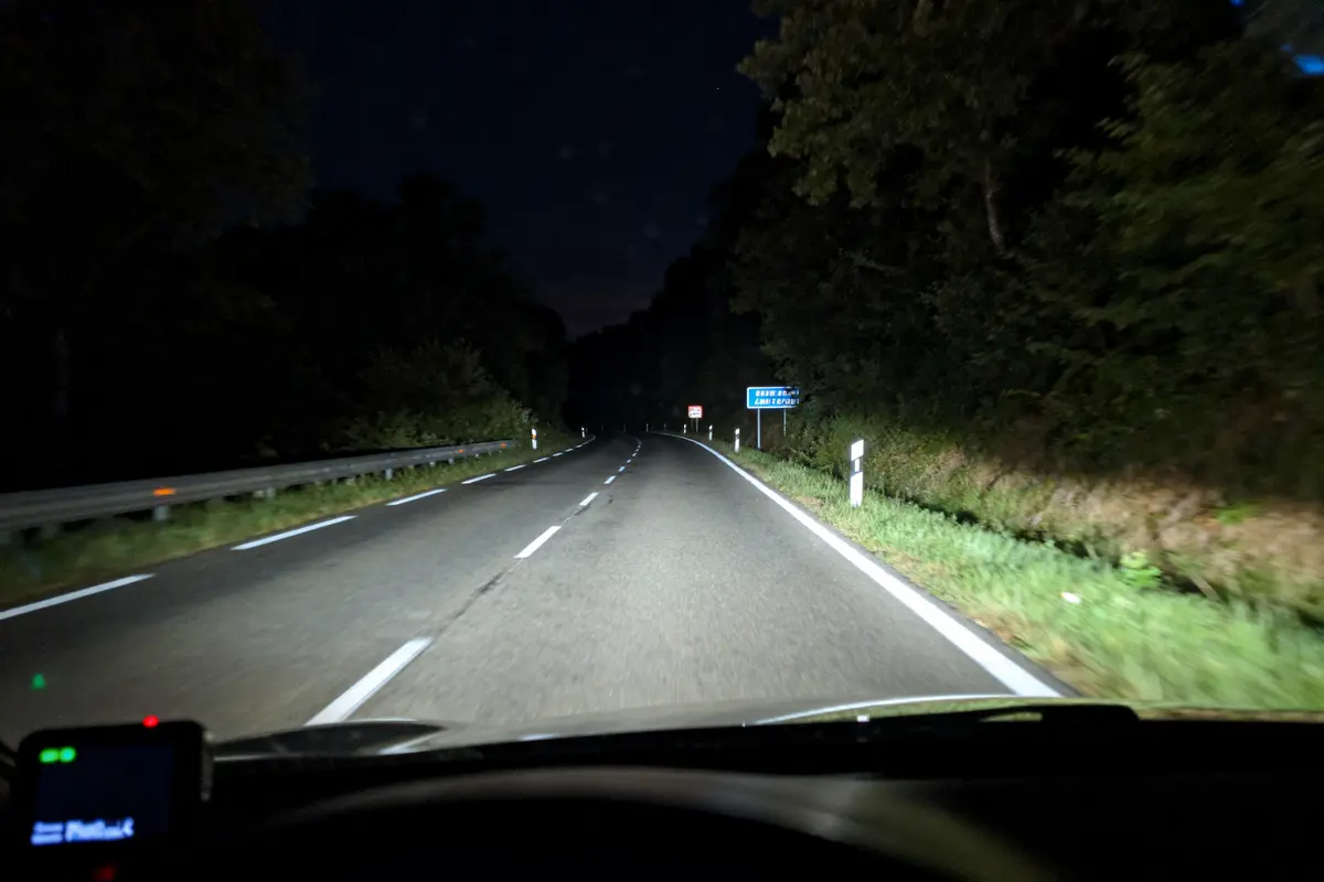 Vue nocturne d'une route forestière éclairée par une dashcam automobile en mouvement