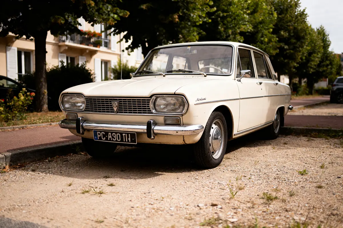 Voiture Simca Ariane blanche stationnée devant des arbres en ville.