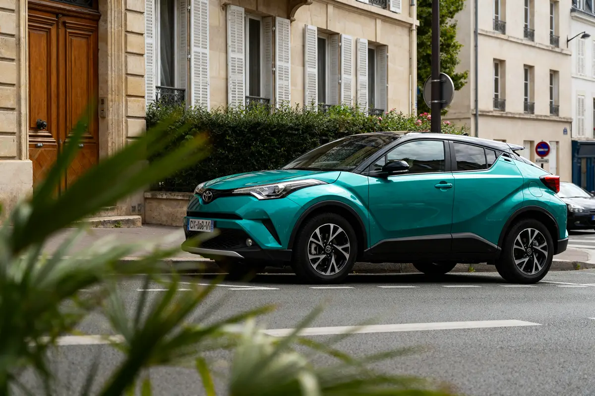 SUV Toyota CHR vert stationné devant une maison parisienne élégante rue tranquille