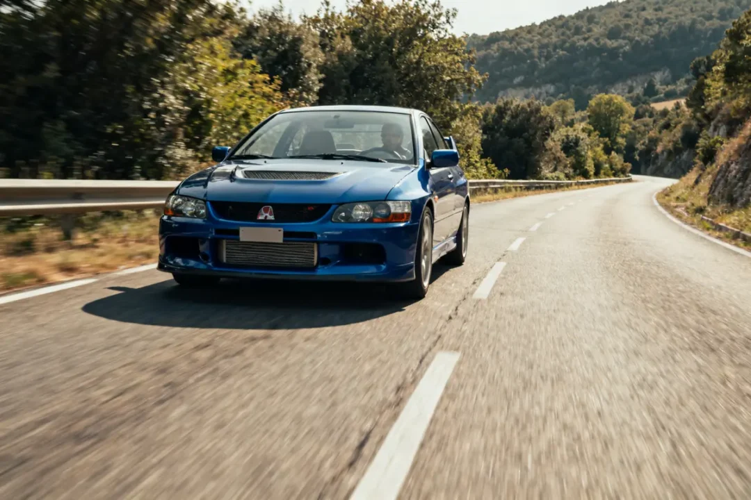 Voiture bleue roulant sur route sinueuse bordée d'arbres ctr Honda