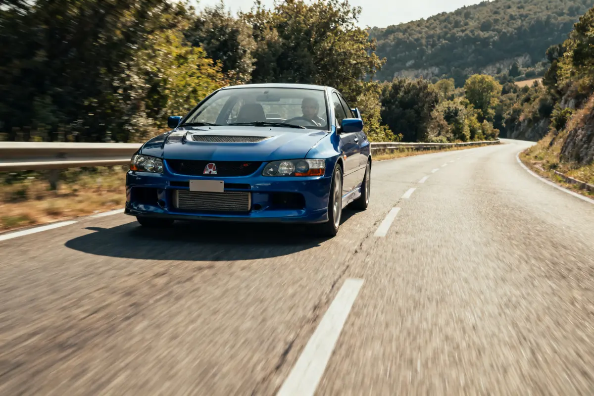 Voiture bleue roulant sur route sinueuse bordée d'arbres ctr Honda