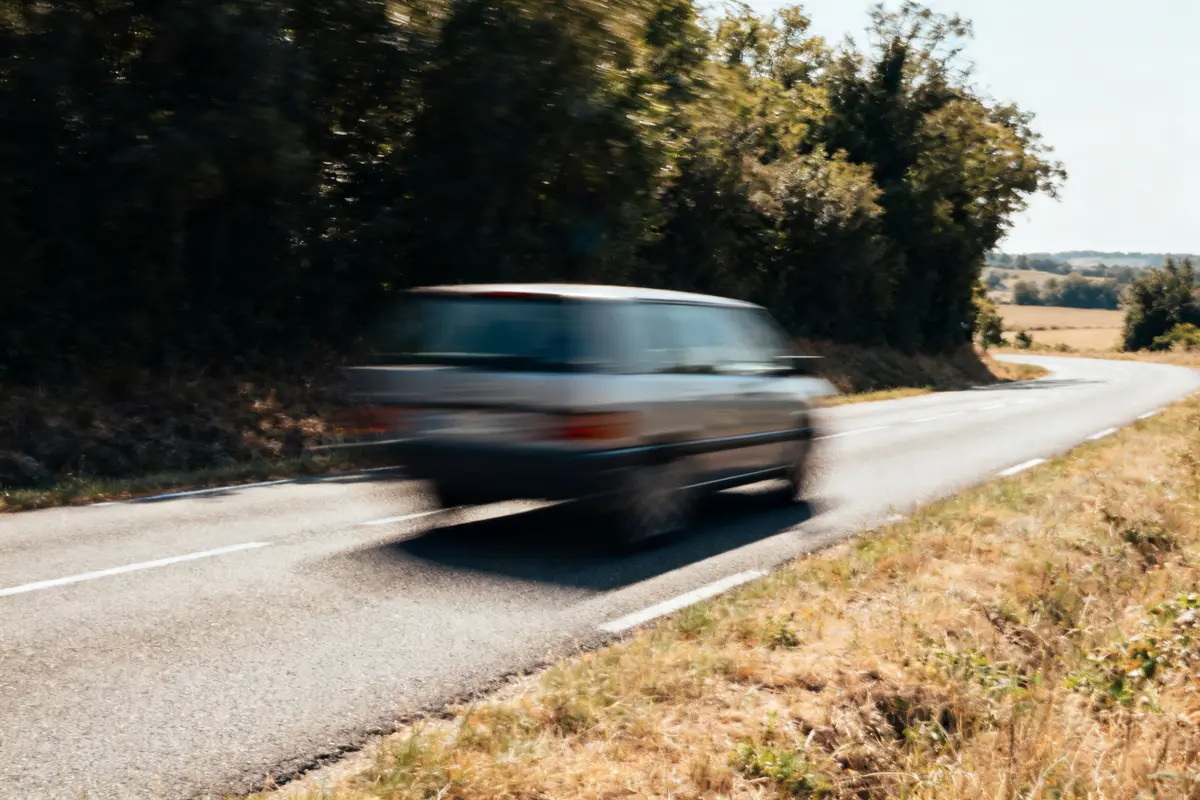 Voiture floue sur route de campagne illustrant un cas d'excès de vitesse rural