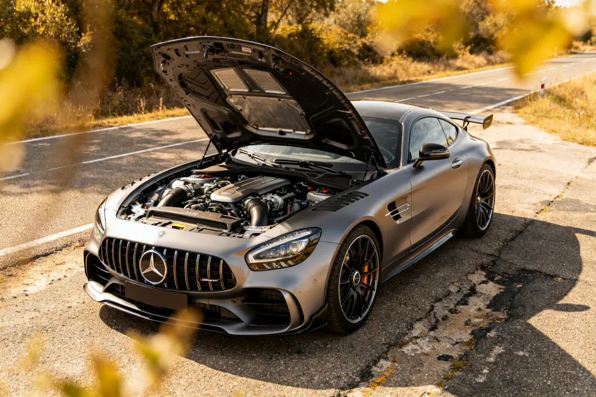 Mercedes-AMG Gran Turismo gris sur route, capot ouvert révélant le moteur puissant