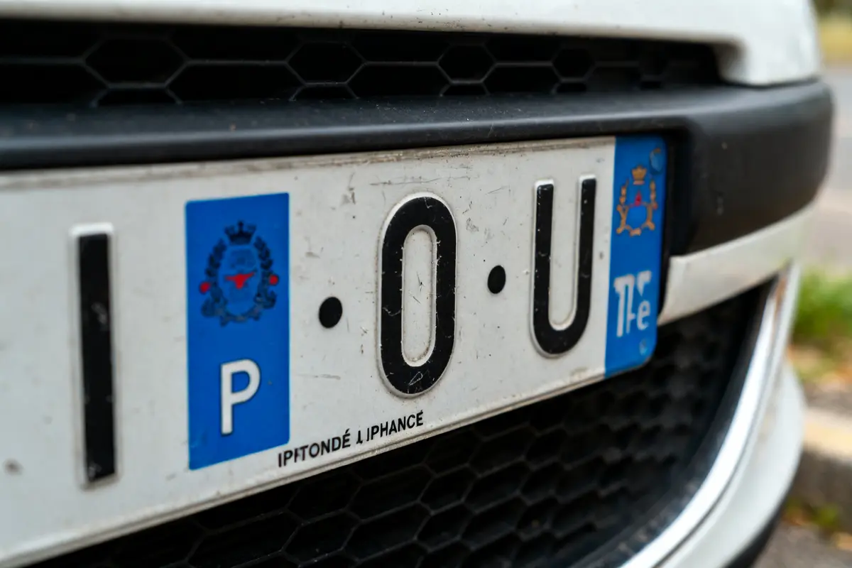 Vue rapprochée d'une plaque d'immatriculation personnalisée sur voiture blanche en stationnement