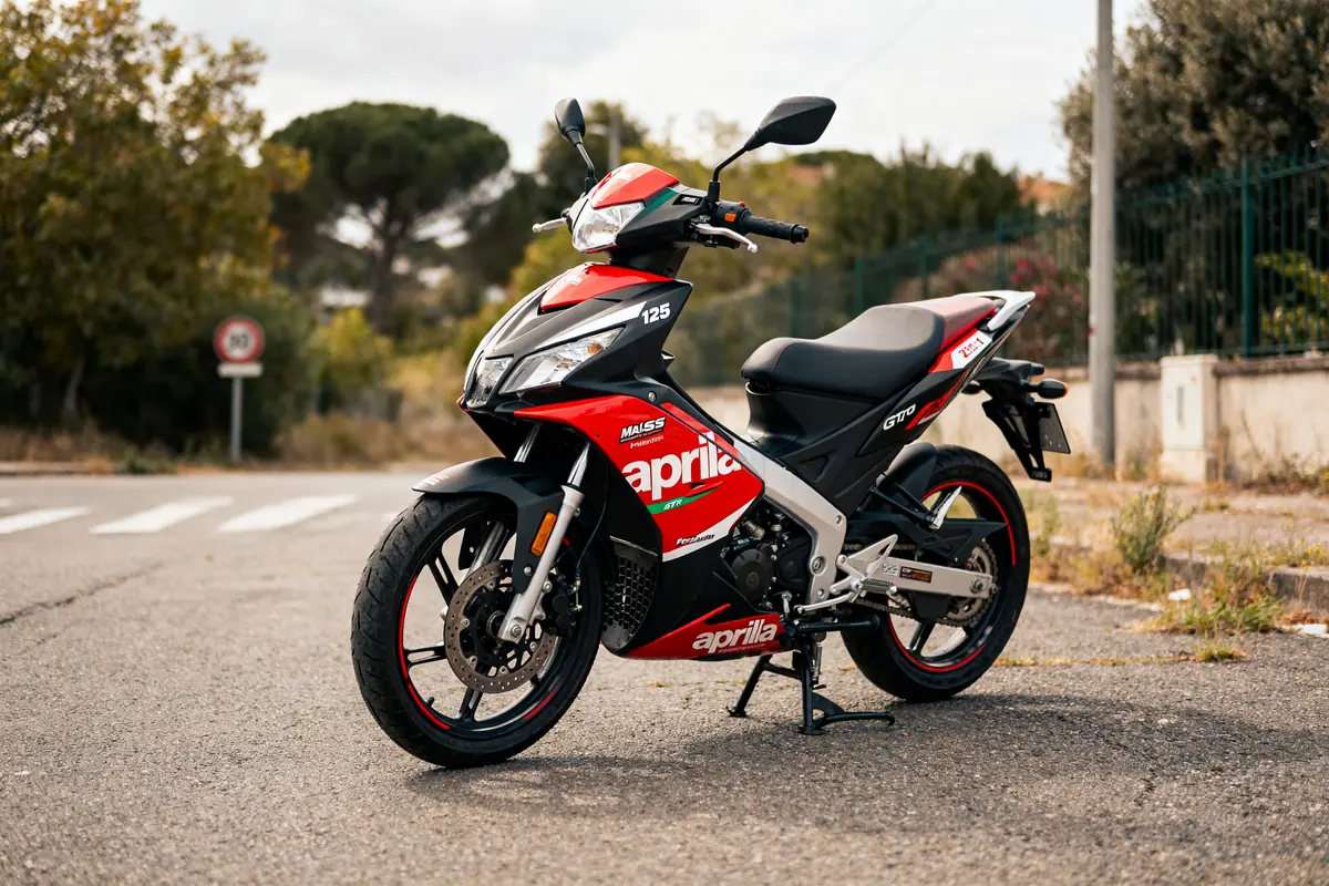 Scooter Aprilia SR GT 125 rouge stationné sur route débridage vitesse max en arrière-plan