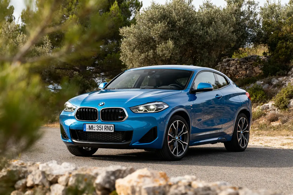 Voiture BMW X2 car bleue stationnée sur route avec nature en arrière-plan