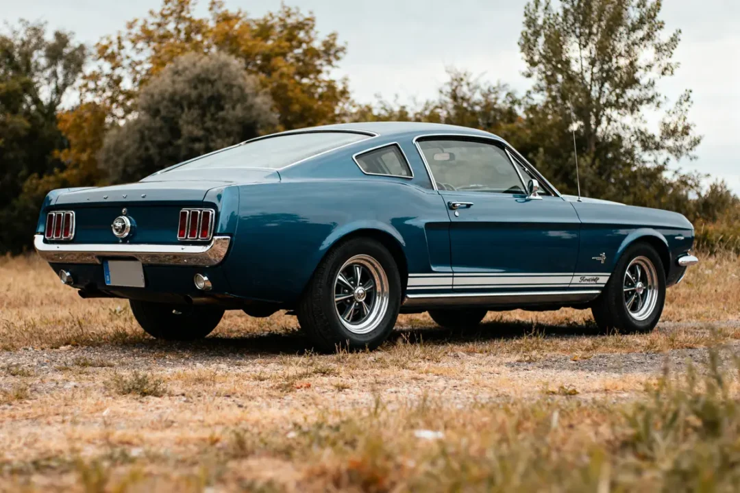 Ford Mustang 1967 bleue garée sur l'herbe avec des arbres en arrière-plan