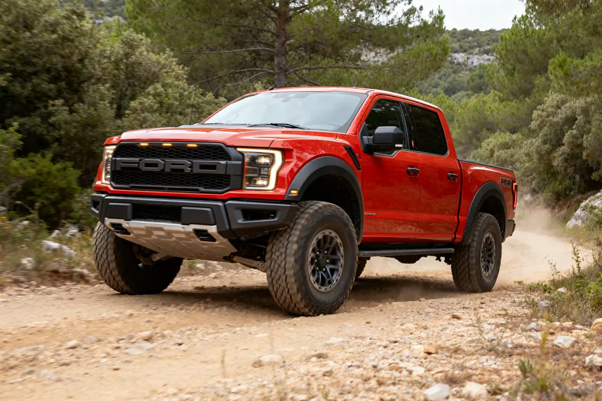 Camion Ford Raptor 4 door rouge sur piste dans la forĂŞt