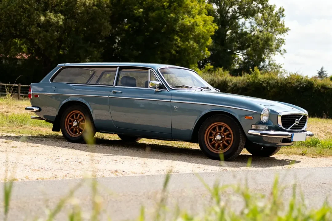 Voiture classique bleu ciel P1800 Volvo wagon garée sur une route ensoleillée.