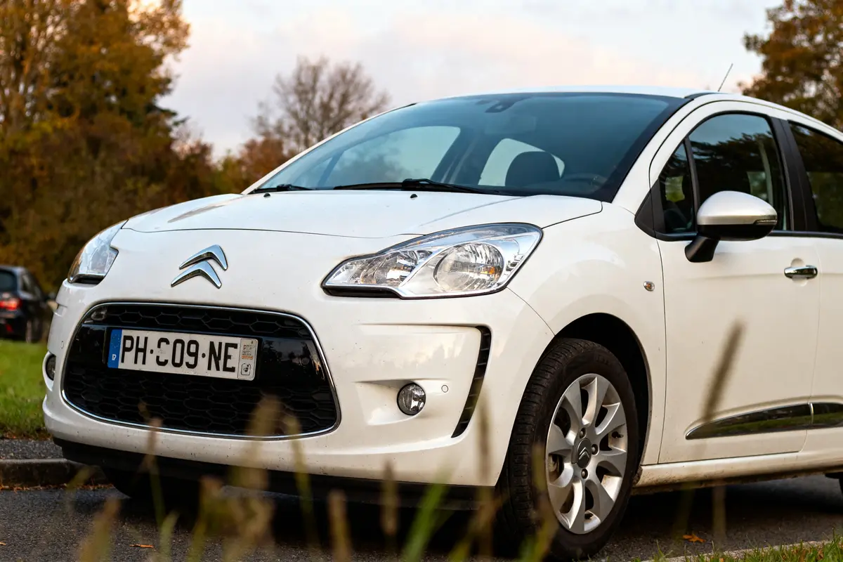 Citroën C3 2012 blanche stationnée sur route devant arbres automnaux sans personne visible