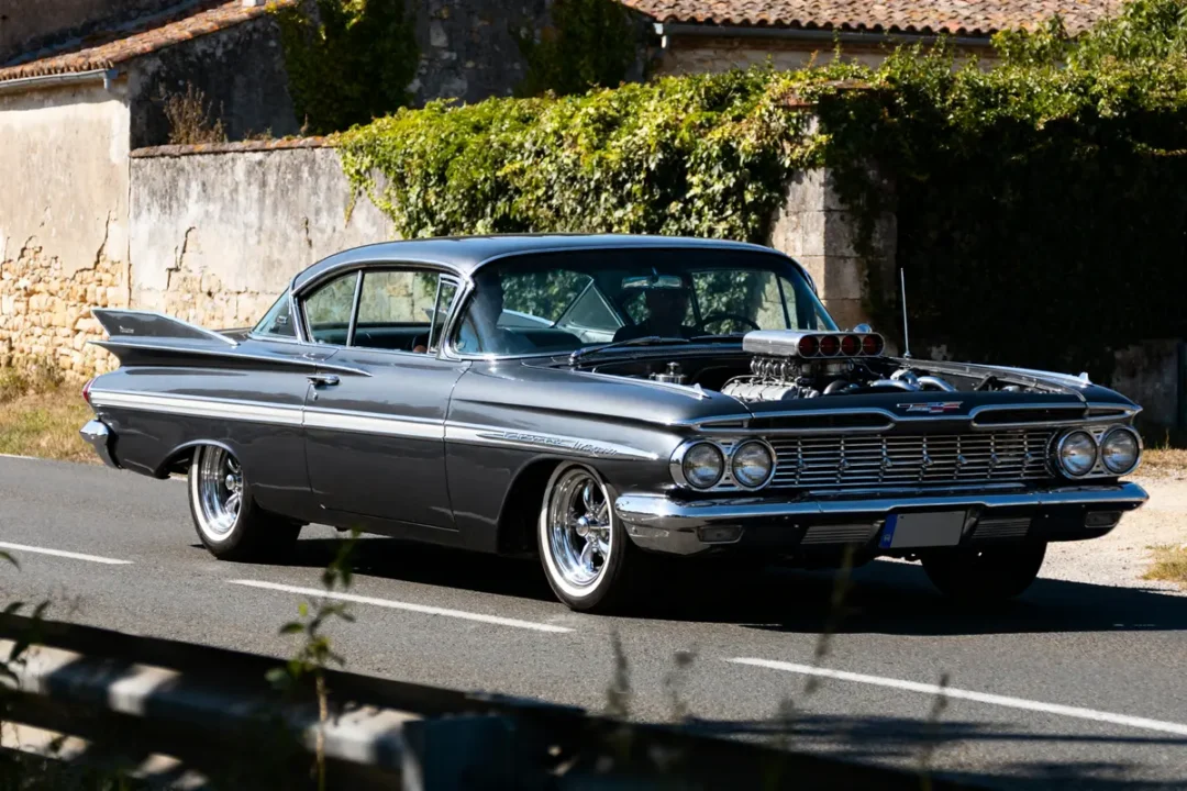 Voiture classique tunée sur route ensoleillée: chevy 1959 impala avec moteur puissant exposé