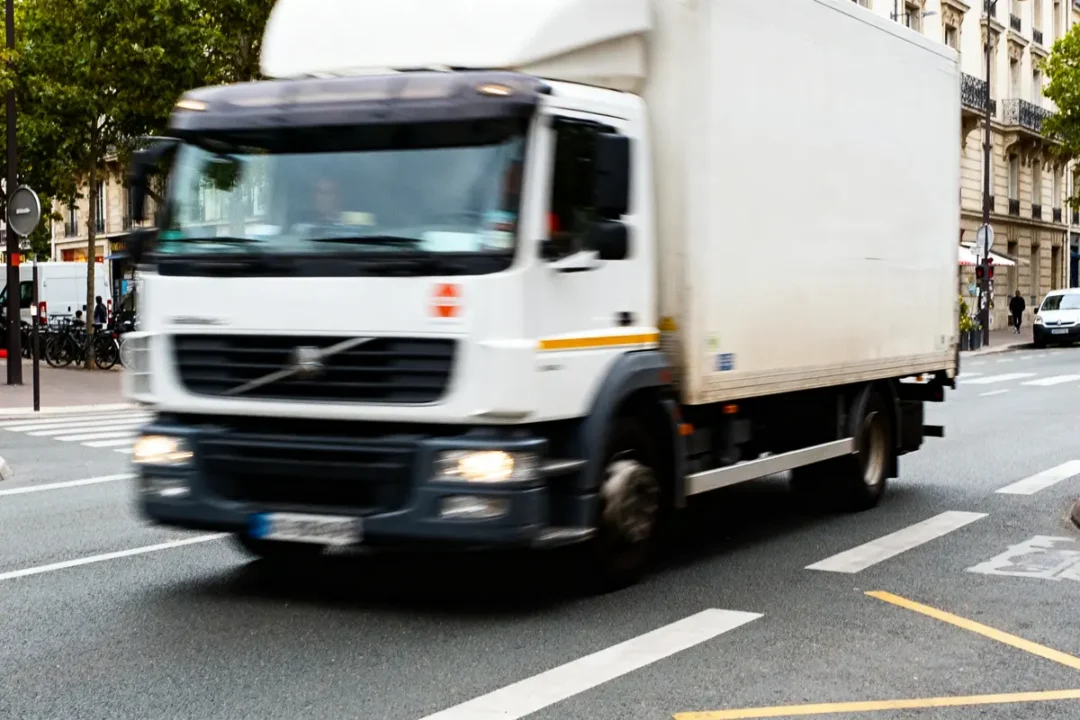 Camion blanc roulant en ville sur la route, illustrant un itineraire camion urbain efficace