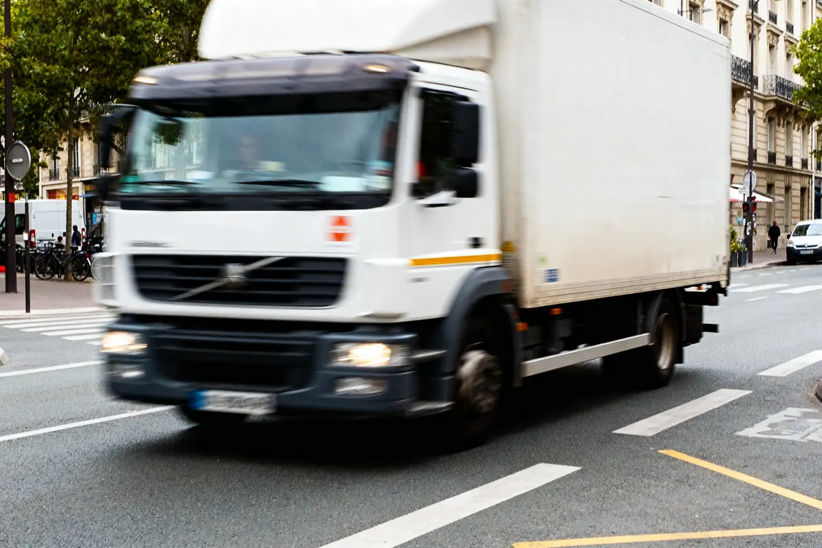 Camion blanc roulant en ville sur la route, illustrant un itineraire camion urbain efficace