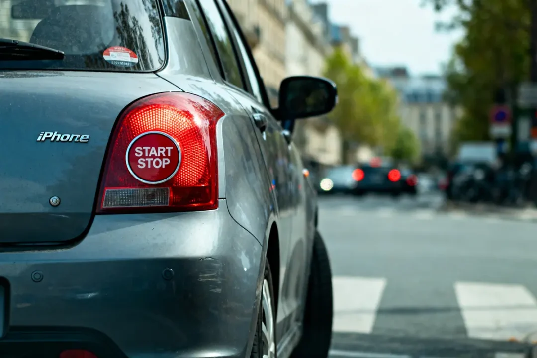 Voiture grise en ville avec un autocollant "START STOP" sur le feu arrière.