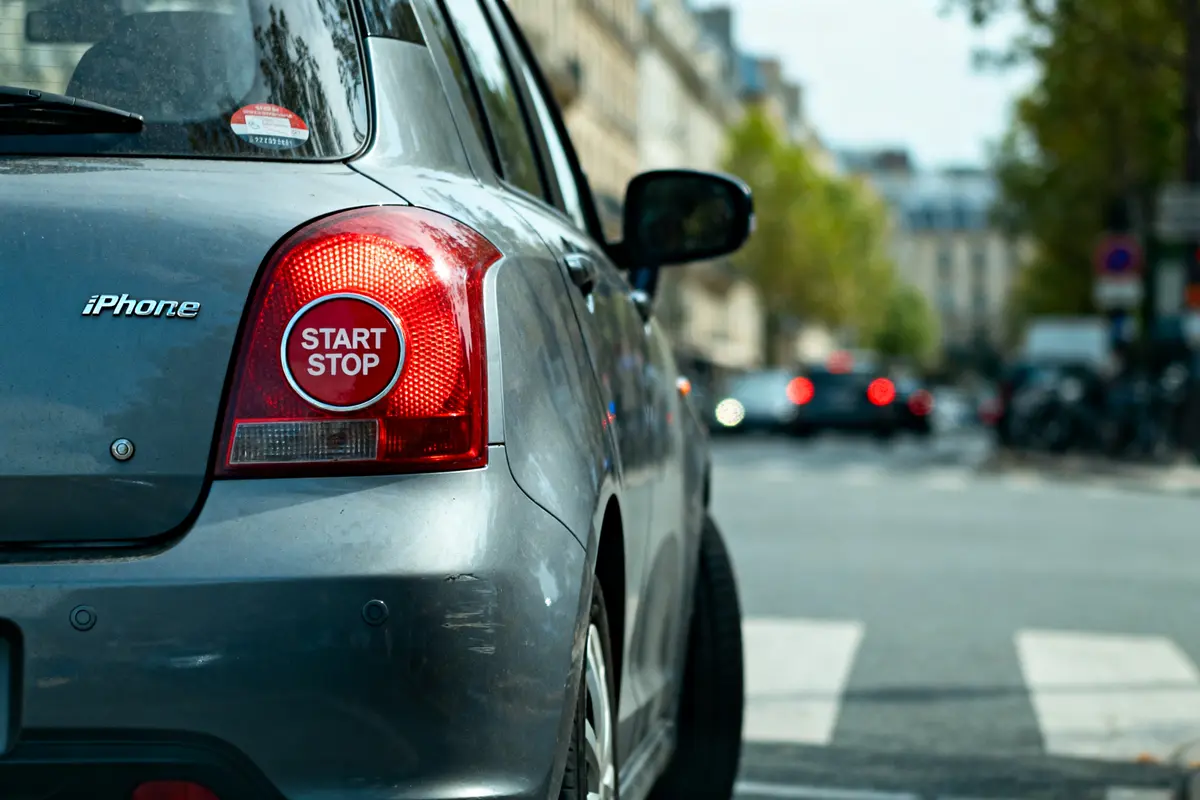 Voiture grise en ville avec un autocollant "START STOP" sur le feu arrière.